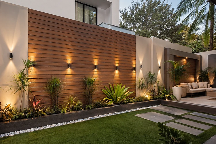 Modern garden feature wall with premium WPC cladding, warm outdoor lighting, landscaping, and contemporary courtyard design.