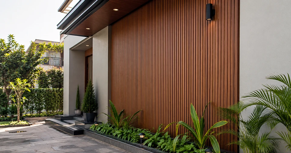 Modern outdoor residential exterior wall in India with premium WPC fluted panels, landscaped plants, and contemporary architectural design.
